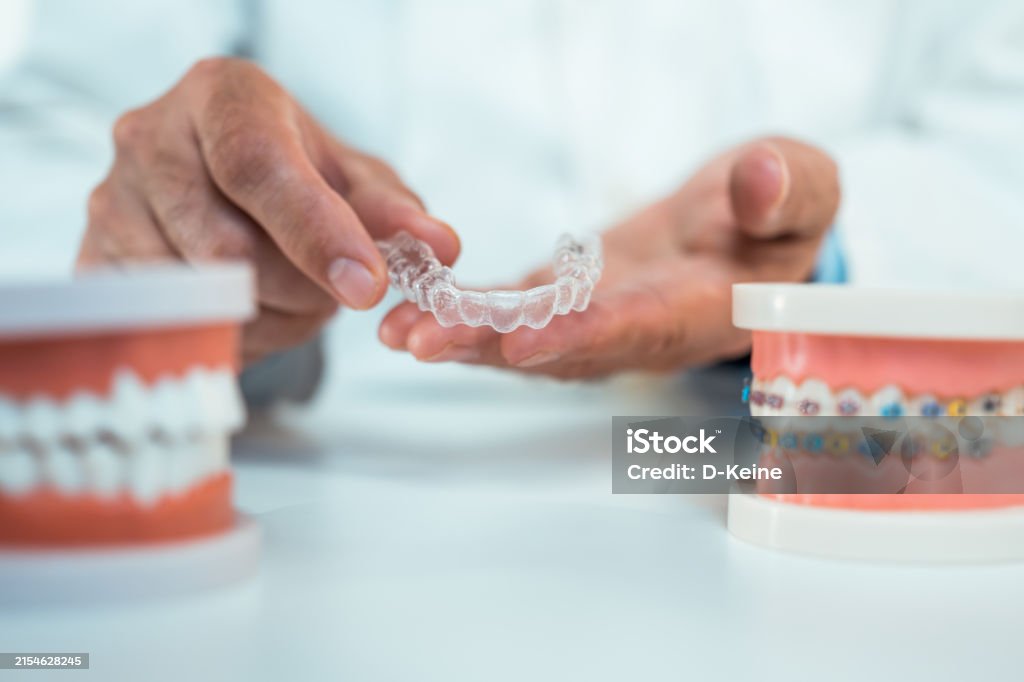 Orthodontist holding transparent dental aligners